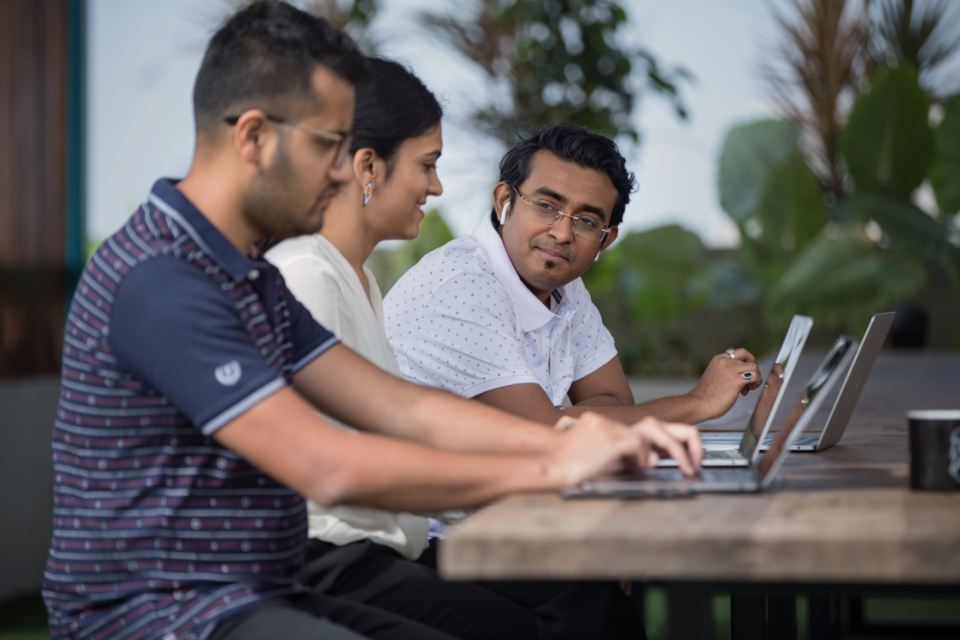 Three colleagues working side by side on laptops