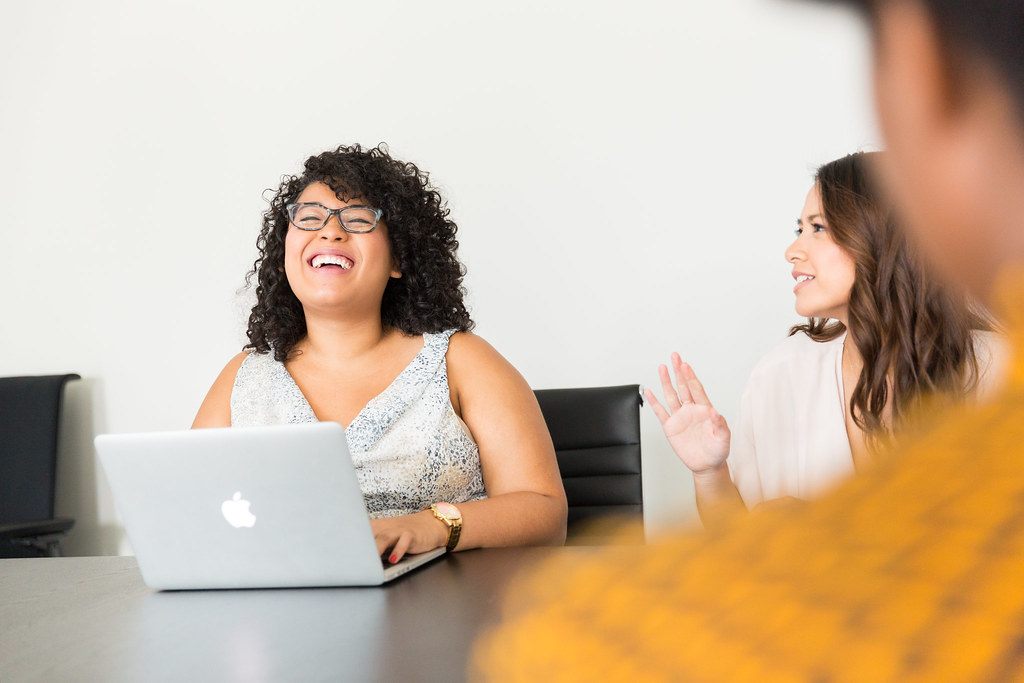 A woman laughing during a conversation at her laptop